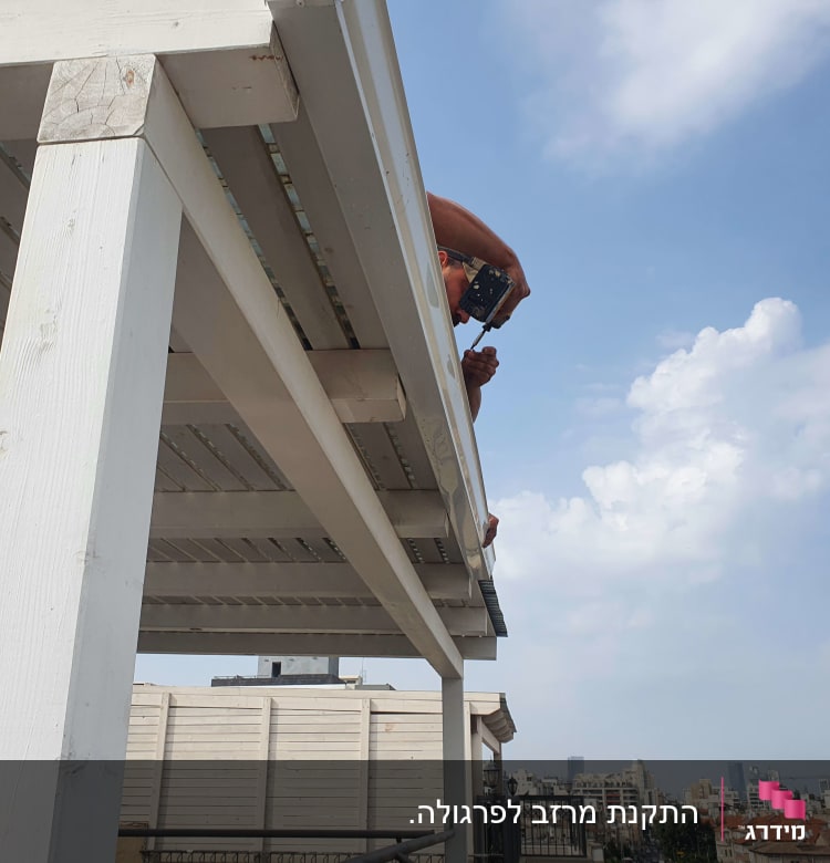 אדם משתמש במקדחה על פרגולה מעץ לבן